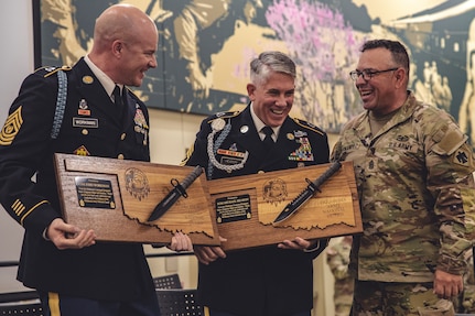 Command Sgt. Maj. John Hernandez (right), state command sergeant major for Oklahoma Army National Guard presents gifts to Command Sgt. Maj. John Workman (Left) of Glenpool, Oklahoma and Sgt. Maj. Michael Hearon (Middle) of Mead, Oklahoma, both members of 1st Battalion, 179th Infantry Regiment, 45th Infantry Brigade Combat Team, during their joint retirement ceremony held at the Norman Armed Forces Reserve Center in Norman, Oklahoma, Saturday, Sept. 14, 2024. Together Workman and Hearon have a combined 61 years of service, including their final assignment as members of the command team for Task Force Tomahawk during their deployment to the Horn of Africa from 2023-2024. (Oklahoma National Guard photo by Staff Sgt. Reece Heck)