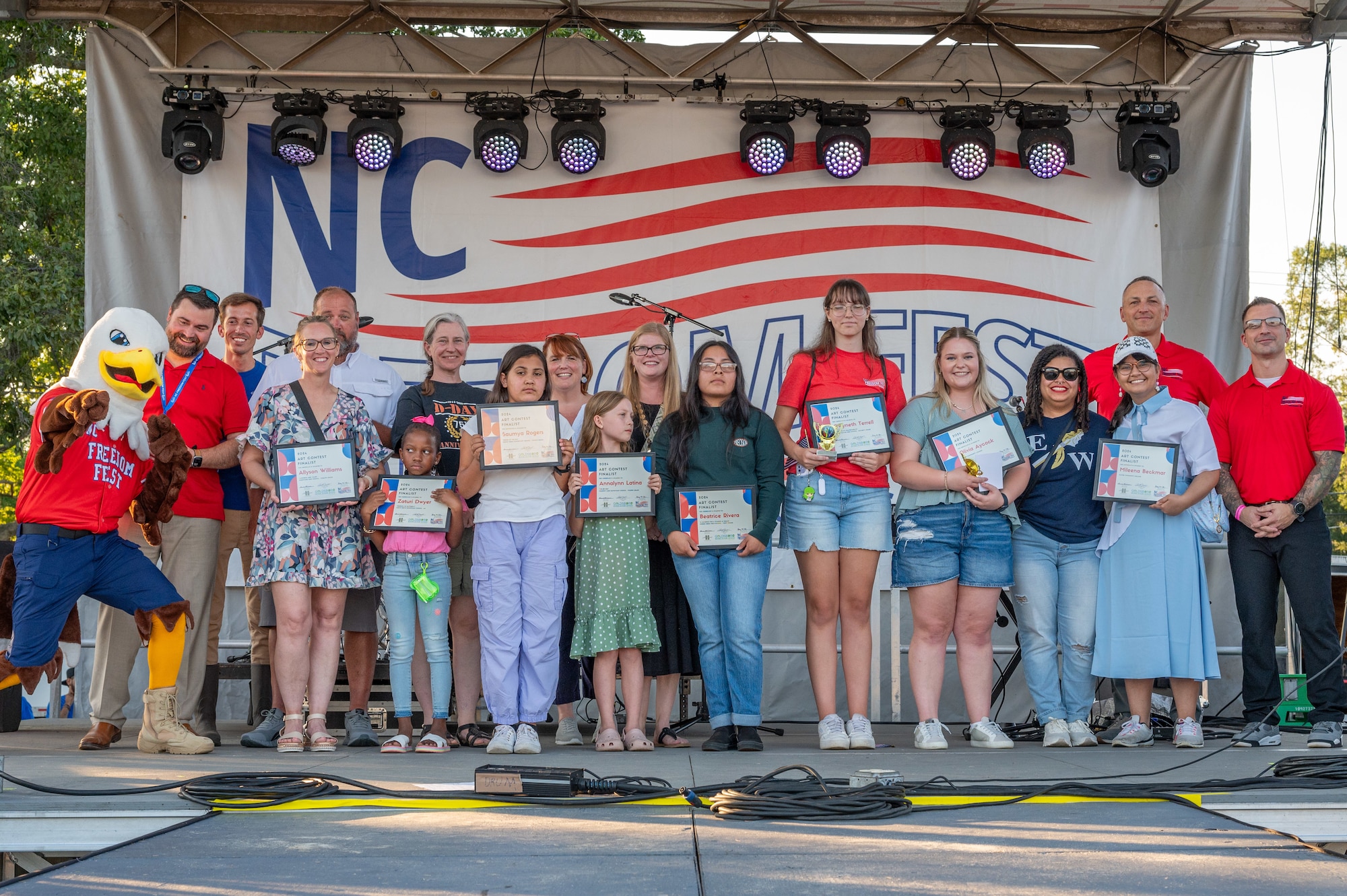 4th FW leaders stand alongside award recipients of a student art contest during an awards ceremony as part of the NC Freedom Fest 2024.