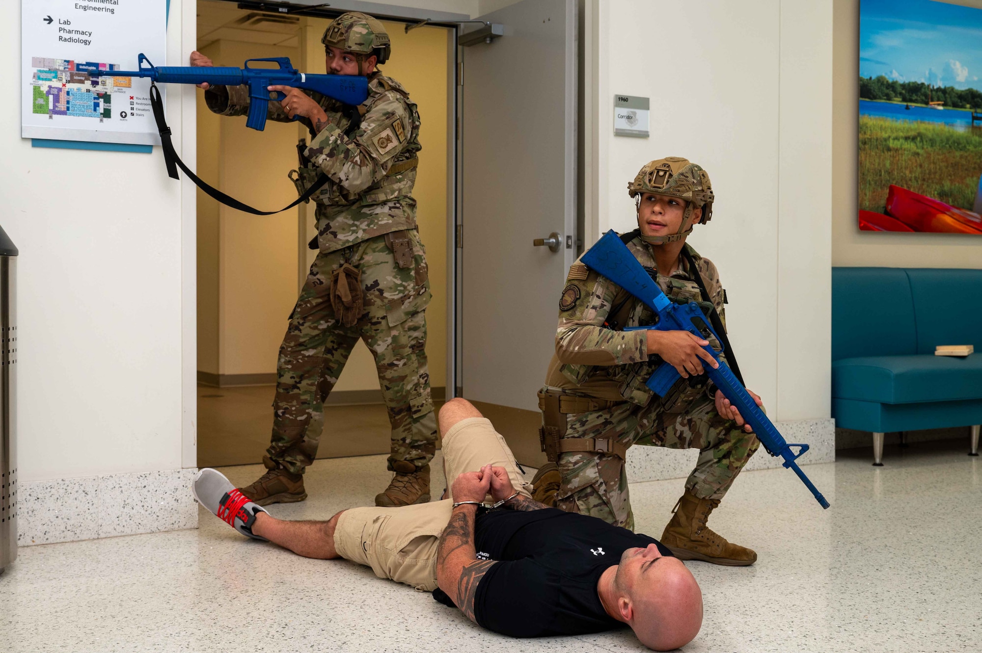 U.S. Air Force Master Sgt. Tyler Dudley, left, 4th Security Forces Squadron flight chief, and Airman Izaiha Diaz, right, 4th SFS installation entry controller, secure the building while Tech Sgt. Peter Sulli, 4th SFS flight sergeant, acts as a simulated active shooter during an active shooter exercise at Seymour Johnson Air Force Base, North Carolina, Sept. 4, 2024. This exercise allows for different agencies across base to maintain preparedness in the event of a real-world scenario. (U.S. Air Force photo by Airman 1st Class Rebecca Tierney