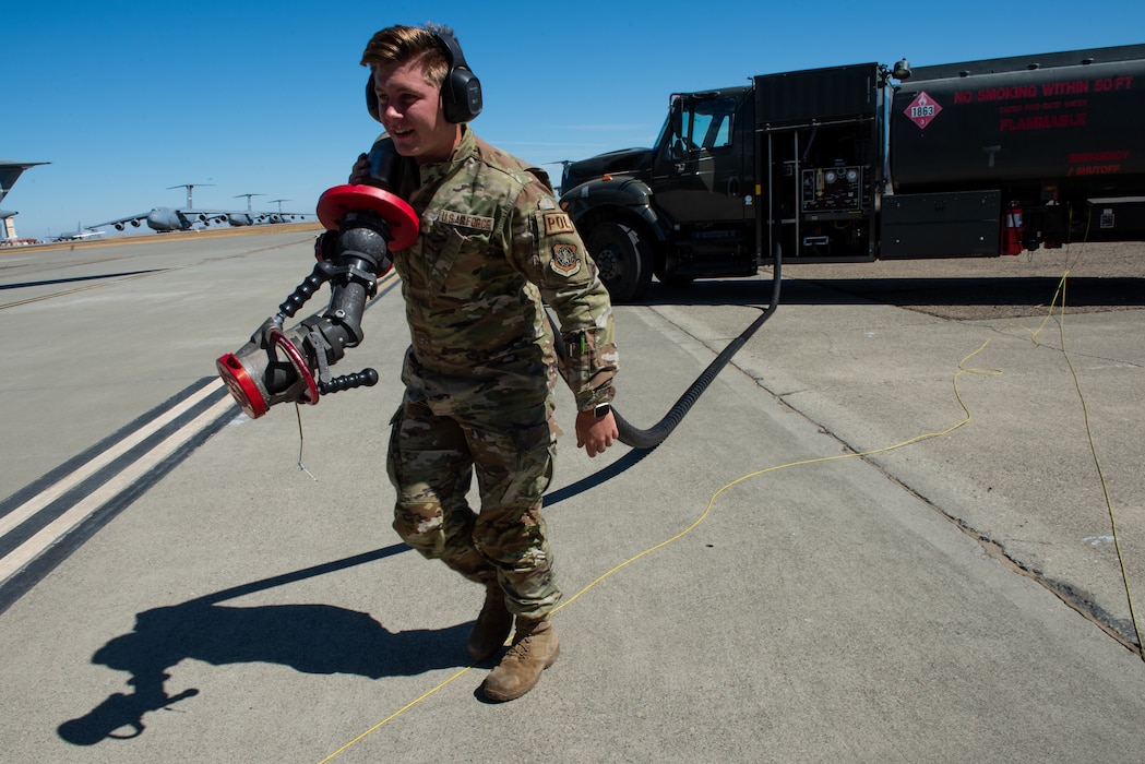 Airman carries fuel hose to aircraft