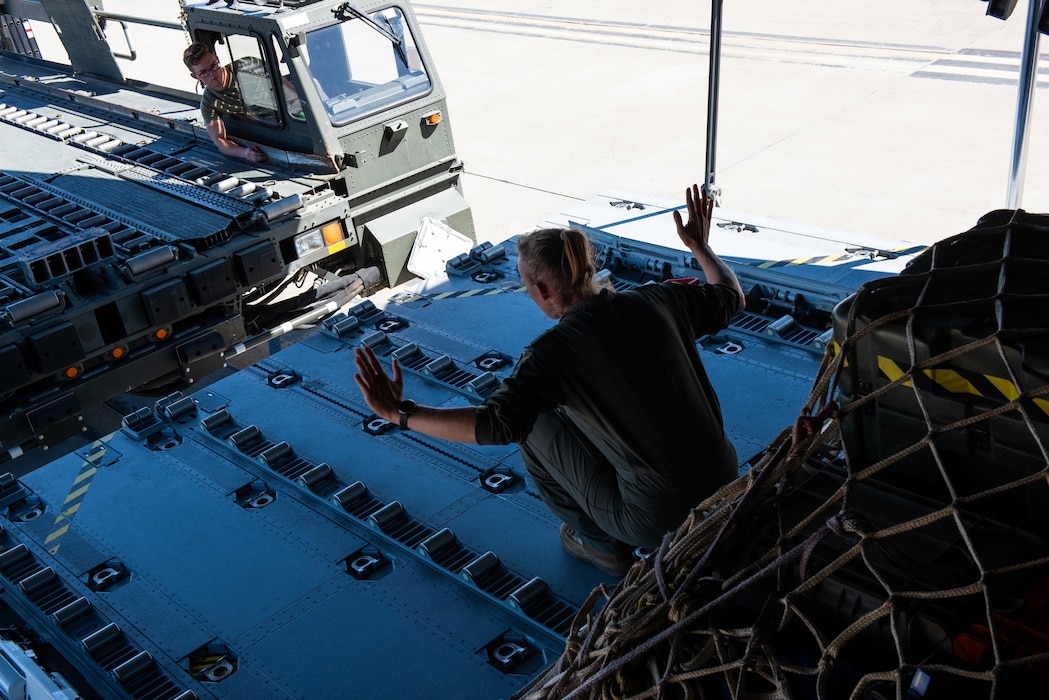 Foreign airman guides a loader closer to an aircraft bay