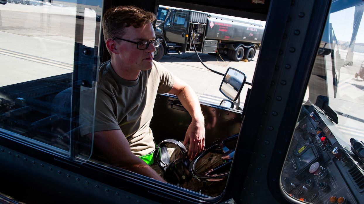 Framing view through a window of Airmen operating a loader