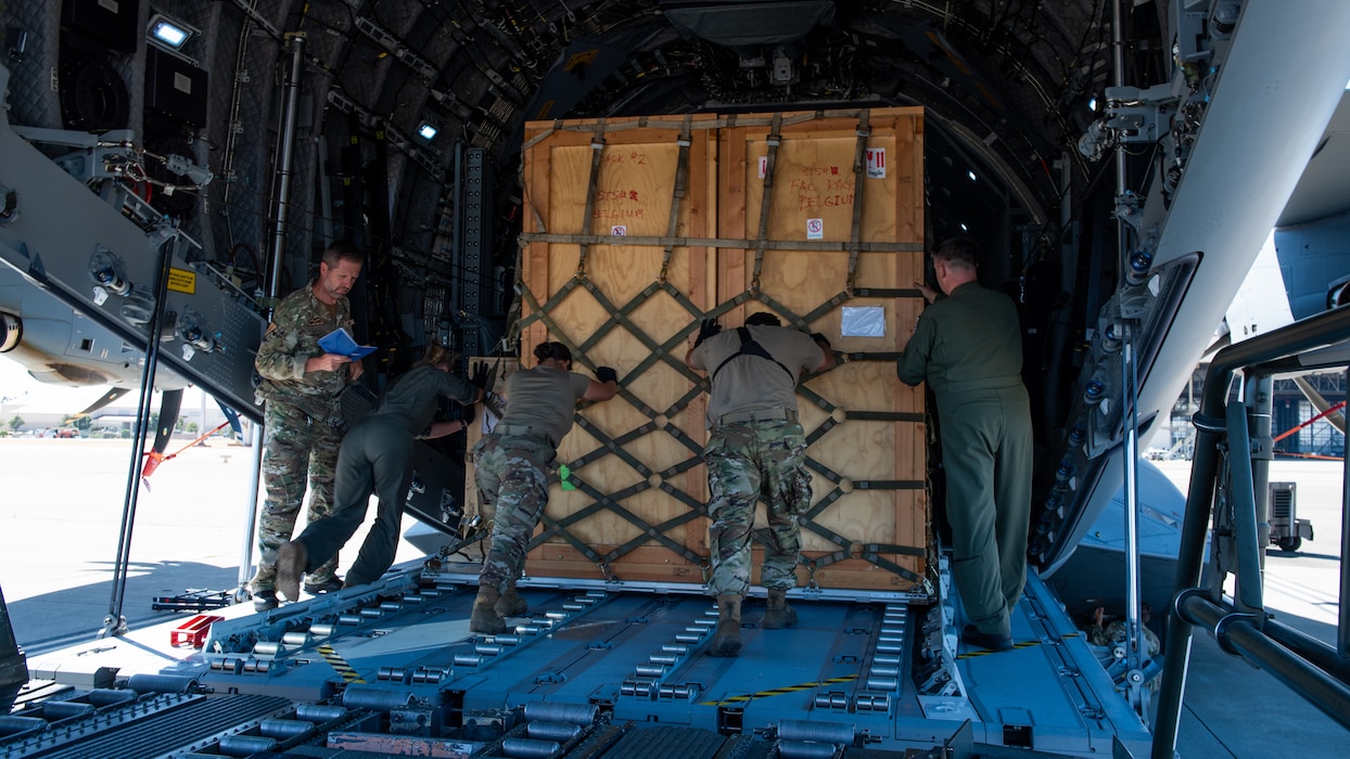 Airmen push crate into aircraft bay