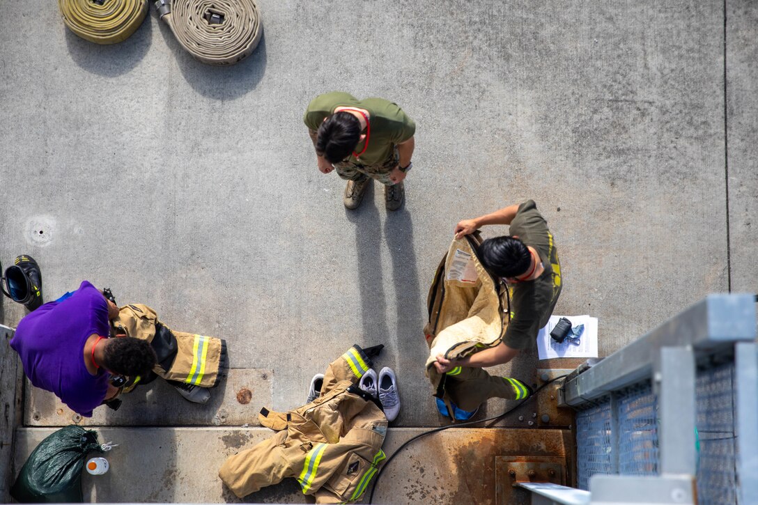 U.S. Marines stationed at Marine Corps Air Station Iwakuni don firefighting gear during the 11th annual 9/11 memorial stair climb at MCAS Iwakuni, Japan, Sept. 11, 2024. Participants climbed 110 floors in honor of those who died during the 9/11 attacks and to simulate a challenge similar to what New York City firefighters endured during rescue operations. (U.S. Marine Corps photo by Lance Cpl. Colin Thibault)