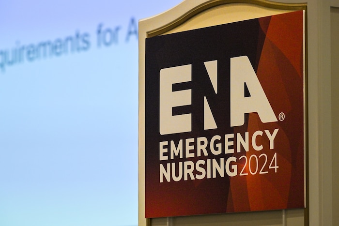 A poster for Emergency Nurse’s Association 2024 convention is displayed on a podium.