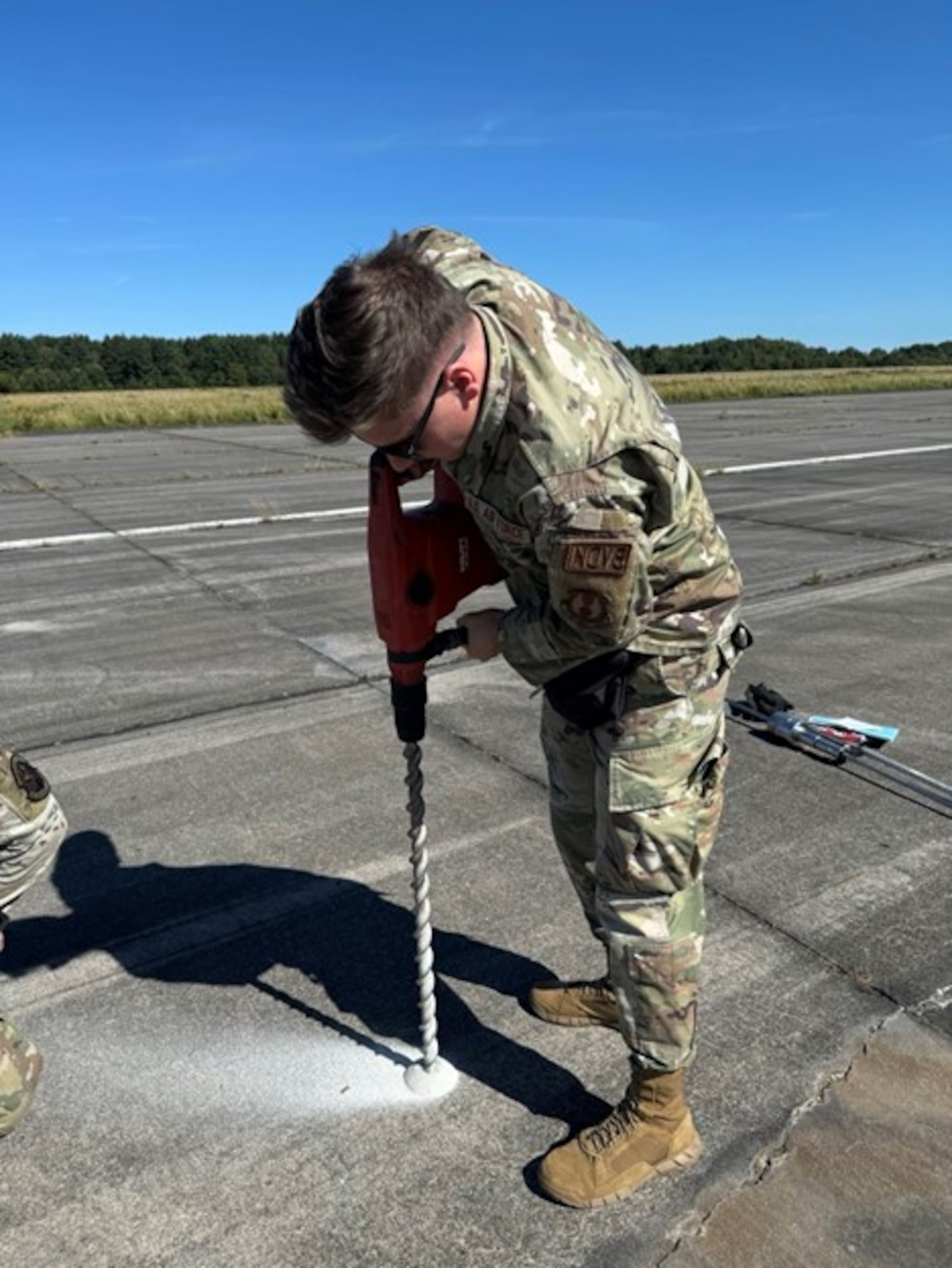 U.S. Air Force 1st Lt. Trevor Akers, a developmental engineer from the 96th Cyberspace Test Group currently supporting the 435th AGOW's Innovation Program, utilizes a drill to bypass a thick layer of concrete to expose the underlying soil in preparation for a Dynamic Cone Penetrometer. These tasks are critical in determining whether a concrete Landing Zone can safely accommodate aircraft, especially in combat zones or remote locations. (U.S. Air Force courtesy photo)