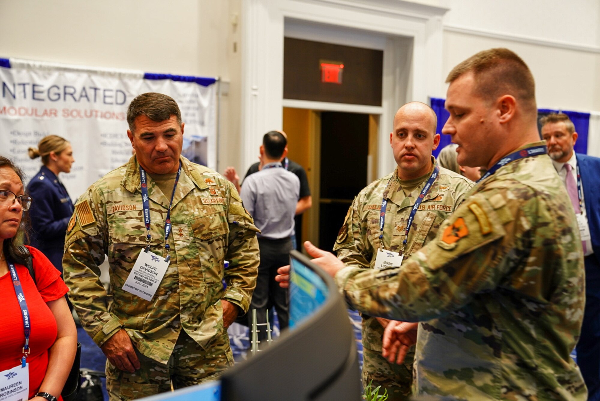 Maj. Gen. Wolfe Davidson, Second Air Force commander, listens as Tech. Sgt. Christopher Gamanche, 333rd Training Squadron Cyber Warfare instructor, discusses his section of the Second Air Force booth at the Air, Space and Cyber Conference, National Harbor, Md., Sept. 16, 2024.