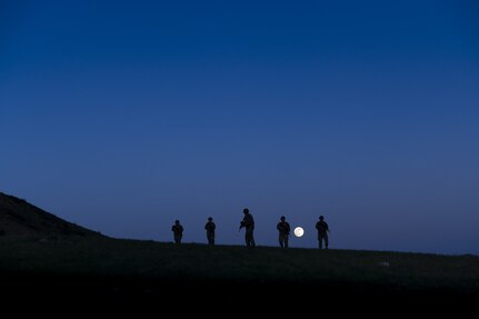 Service members patrol at night.