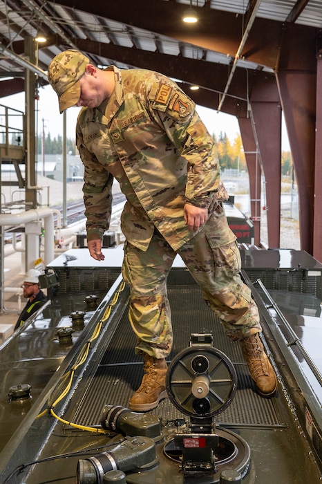 U.S. Air Force Staff Sgt. Matthew Landon, 354th Logistics Readiness Squadron mobile distribution noncommissioned officer in charge, inspects the fuel level through a viewing hole on the top of the fuel tank of an R11 aircraft refueling vehicle at North Pole, Alaska, Sept. 13, 2024.