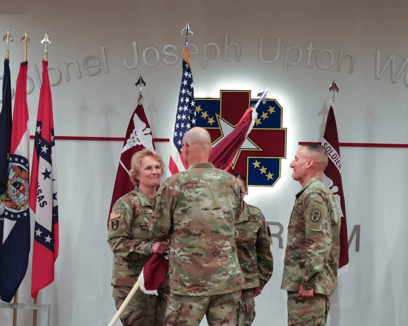 Medical Readiness Command East Commanding General, Brigadier General Lance Raney, passes the colors and all that it represents to incoming commander Col. Stephanie Mont during the Womack Army Medical Center Change of Command Ceremony, September 17, 2024, Weaver Auditorium.