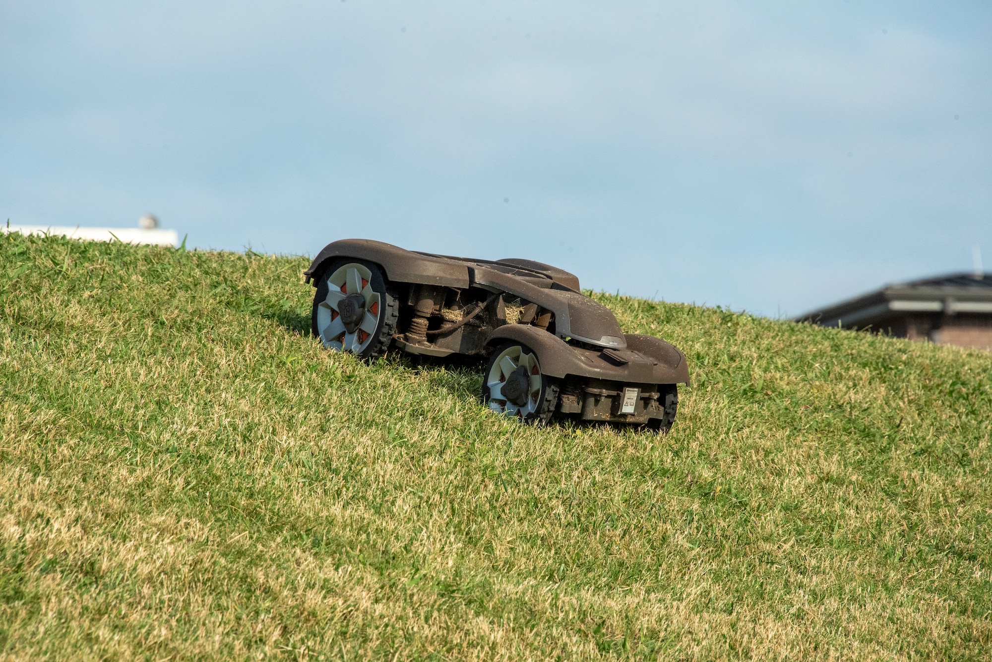 A robotic mower trimming grass on a hillside.