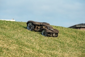 A robotic mower trimming grass on a hillside.