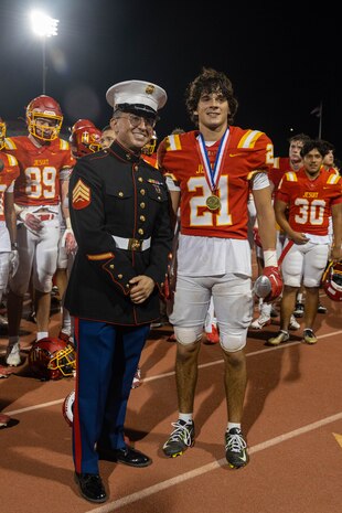 U.S. Marine Corps Sgt. Andrew Cortez, a canvassing recruiter with Recruiting Station Sacramento, left, stands with the Most Valuable Football player for Jesuit High School during a Great American Rivalry Series game at Hughes Stadium in Sacramento, California, Sept. 14, 2024. The Great American Rivalry Series shines the spotlight on top high school football rivalries across the nation, where long-standing traditions are valued, expectations are sky high, and followers are passionate and loyal. (U.S. Marine Corps photo by Staff Sgt. Ryan Harvey)