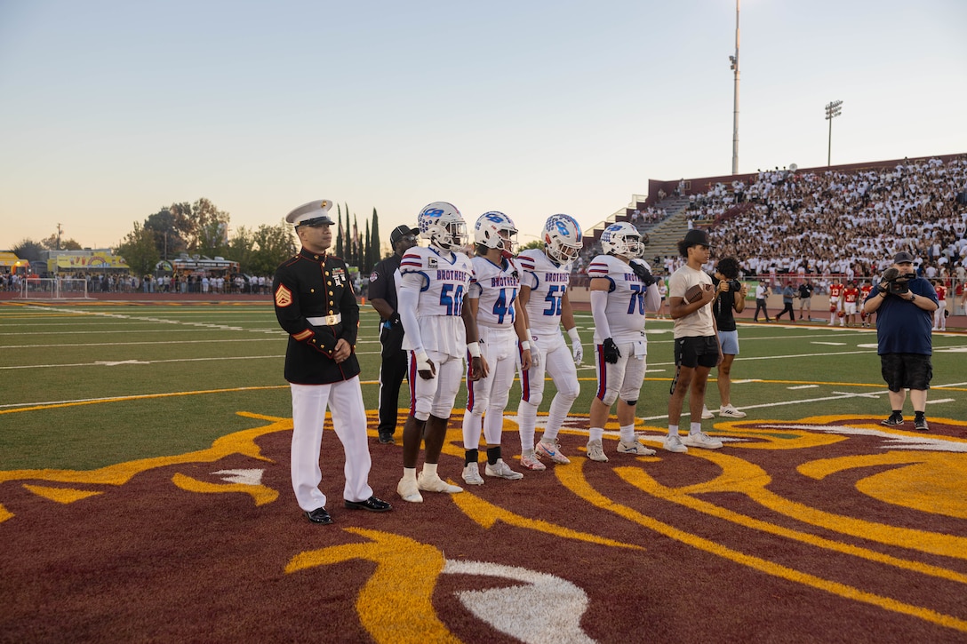 U.S. Marine Corps Staff Sgt. Joey Montry, a canvassing recruiter with Recruiting Station Sacramento, left, stands with Christian Brothers High School players during a Great American Rivalry Series game at Hughes Stadium in Sacramento, California, Sept. 14, 2024. The Great American Rivalry Series shines the spotlight on top high school football rivalries across the nation, where long-standing traditions are valued, expectations are sky high, and followers are passionate and loyal. (U.S. Marine Corps photo by Staff Sgt. Ryan Harvey)