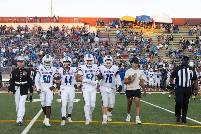U.S. Marine Corps Staff Sgt. Joey Montry, a canvassing recruiter with Recruiting Station Sacramento, left, escorts Christian Brothers High School football players to center field for the coin toss during a Great American Rivalry Series game at Hughes Stadium in Sacramento, California, Sept. 14, 2024. The Great American Rivalry Series shines the spotlight on top high school football rivalries across the nation, where long-standing traditions are valued, expectations are sky high, and followers are passionate and loyal. (U.S. Marine Corps photo by Staff Sgt. Ryan Harvey)