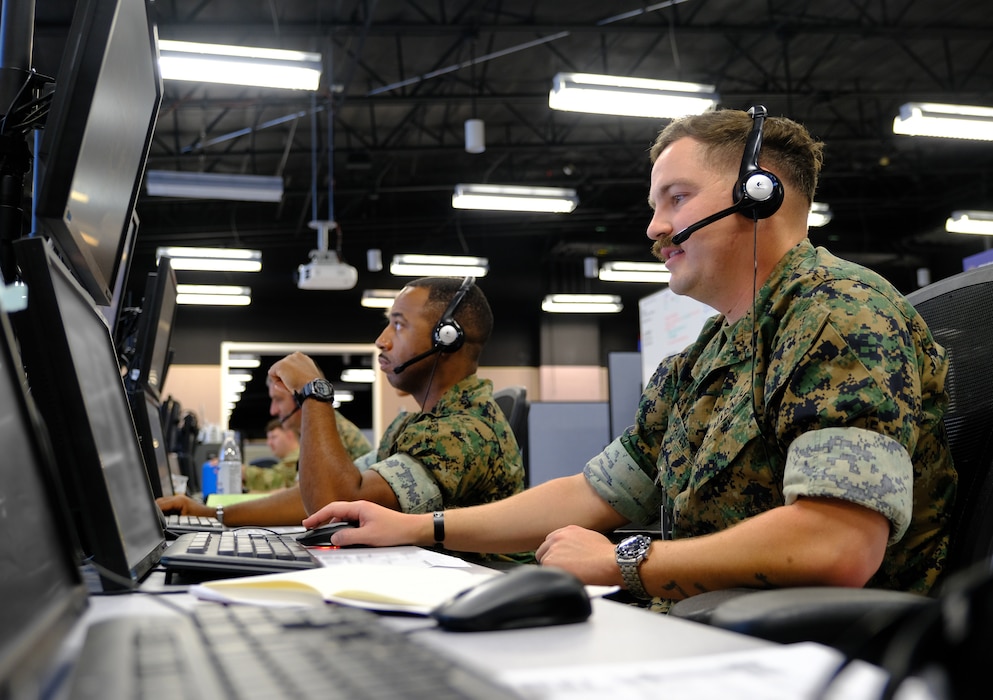 two uniformed U.S. Navy Sailors work at a computer