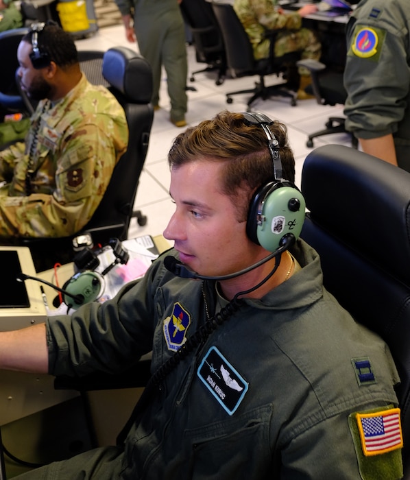 uniformed U.S. Airmen fly in simulator