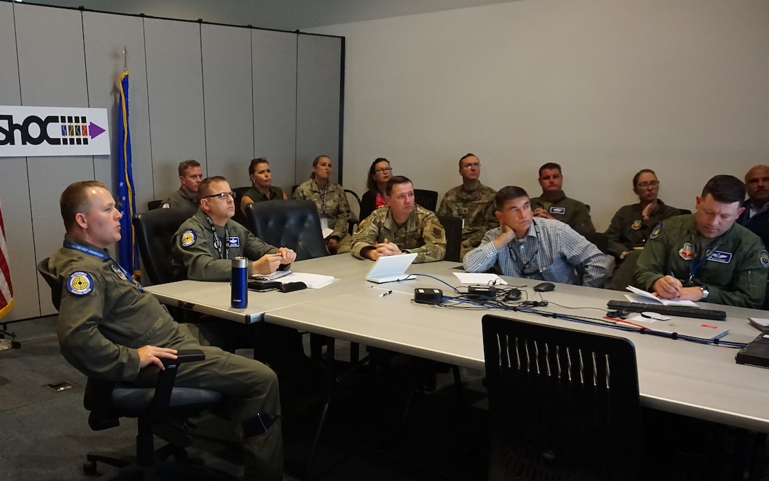 uniformed U.S. Air Force Airmen sit at a conference table looking forward