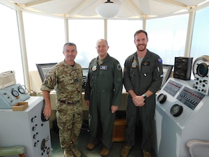 a uniformed U.S. Airman. A uniformed Royal Air Force member and a Royal Australian Air Force member stand together