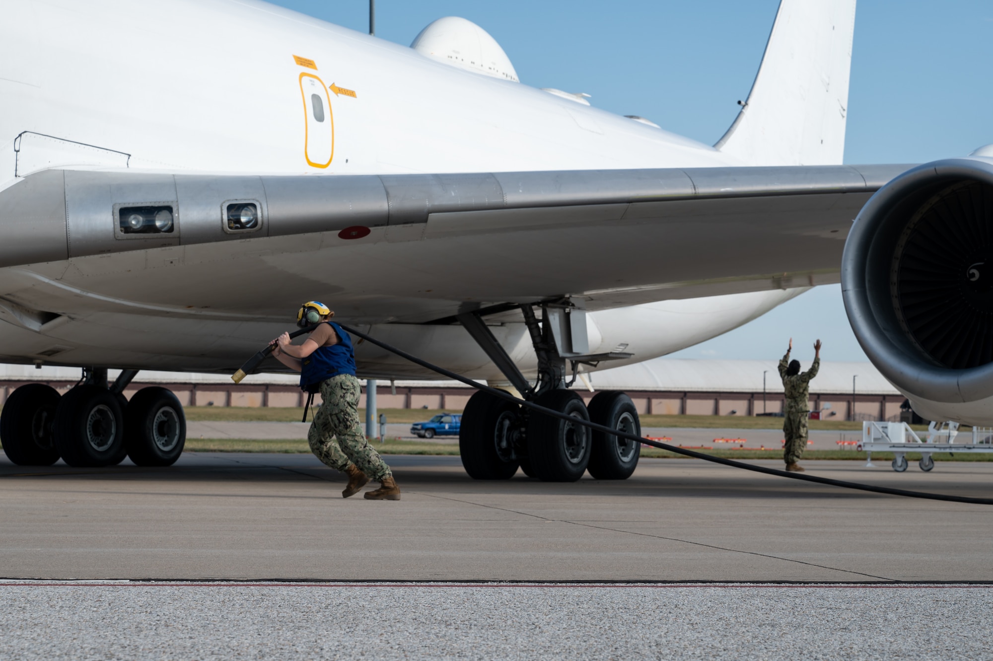 An aviation electrician hauls a cable from a generator to a E-6B Mercury