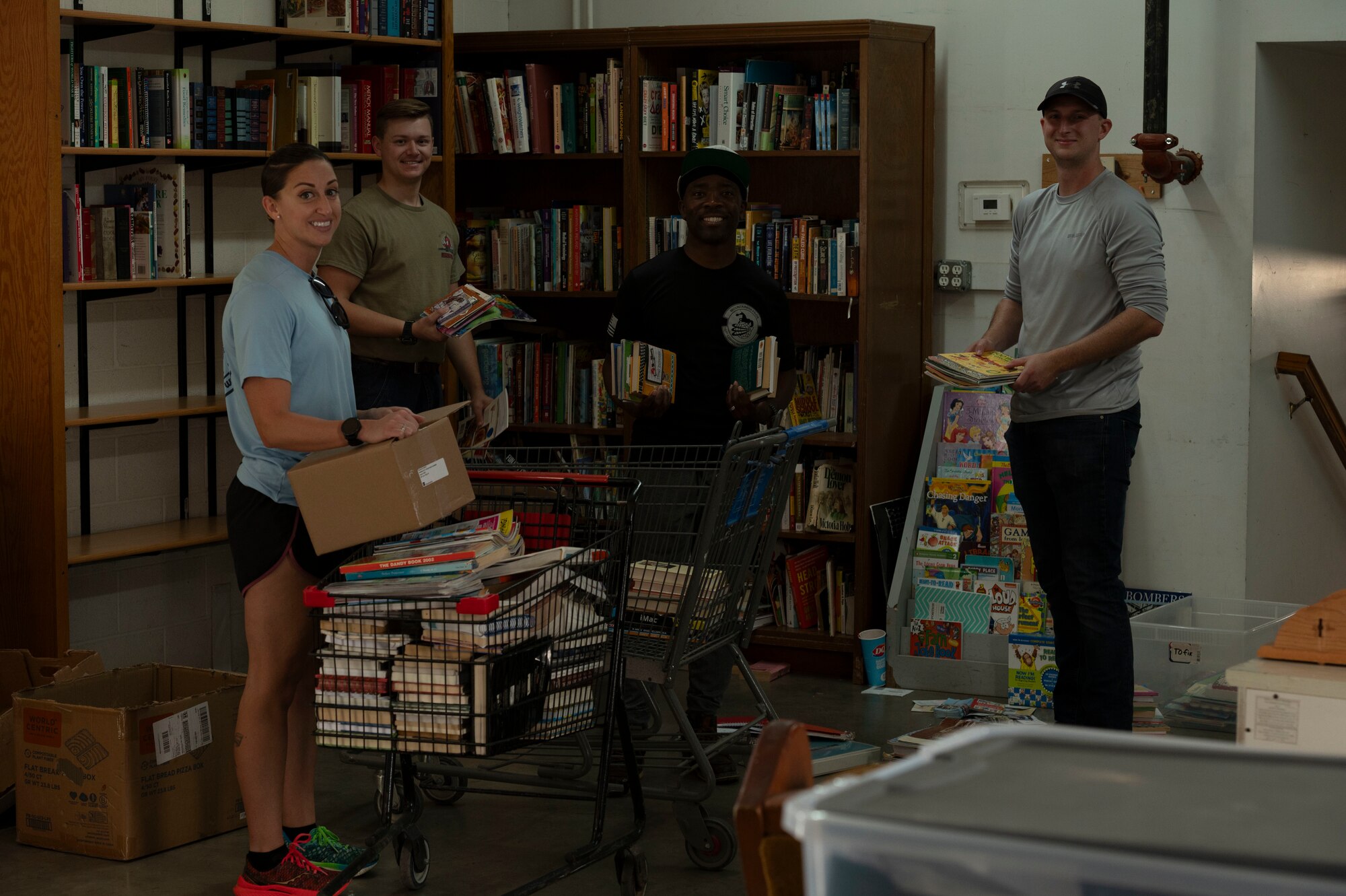 two men and a woman stand in a small library
