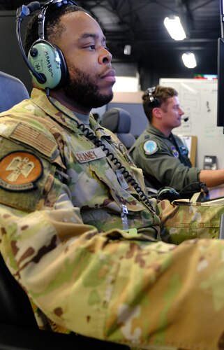 uniformed U.S. Airmen fly in simulator