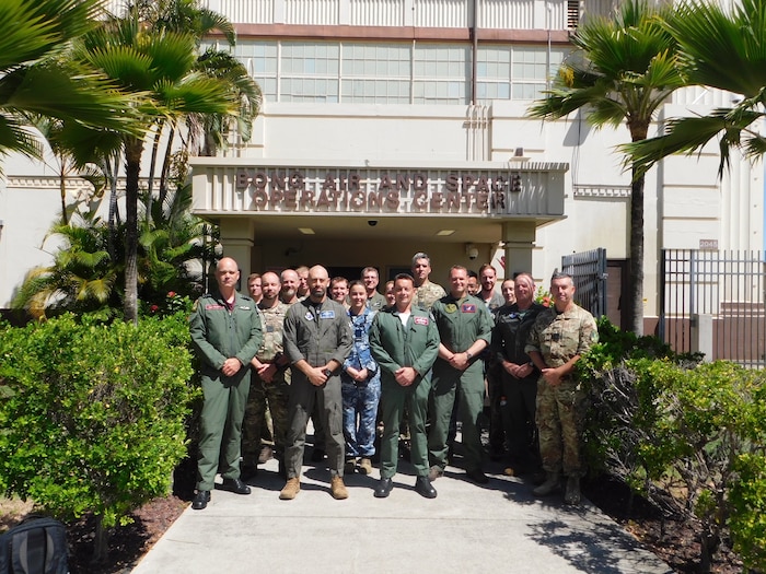 a group of uniformed Australian and United Kingdom members stand outside of a building