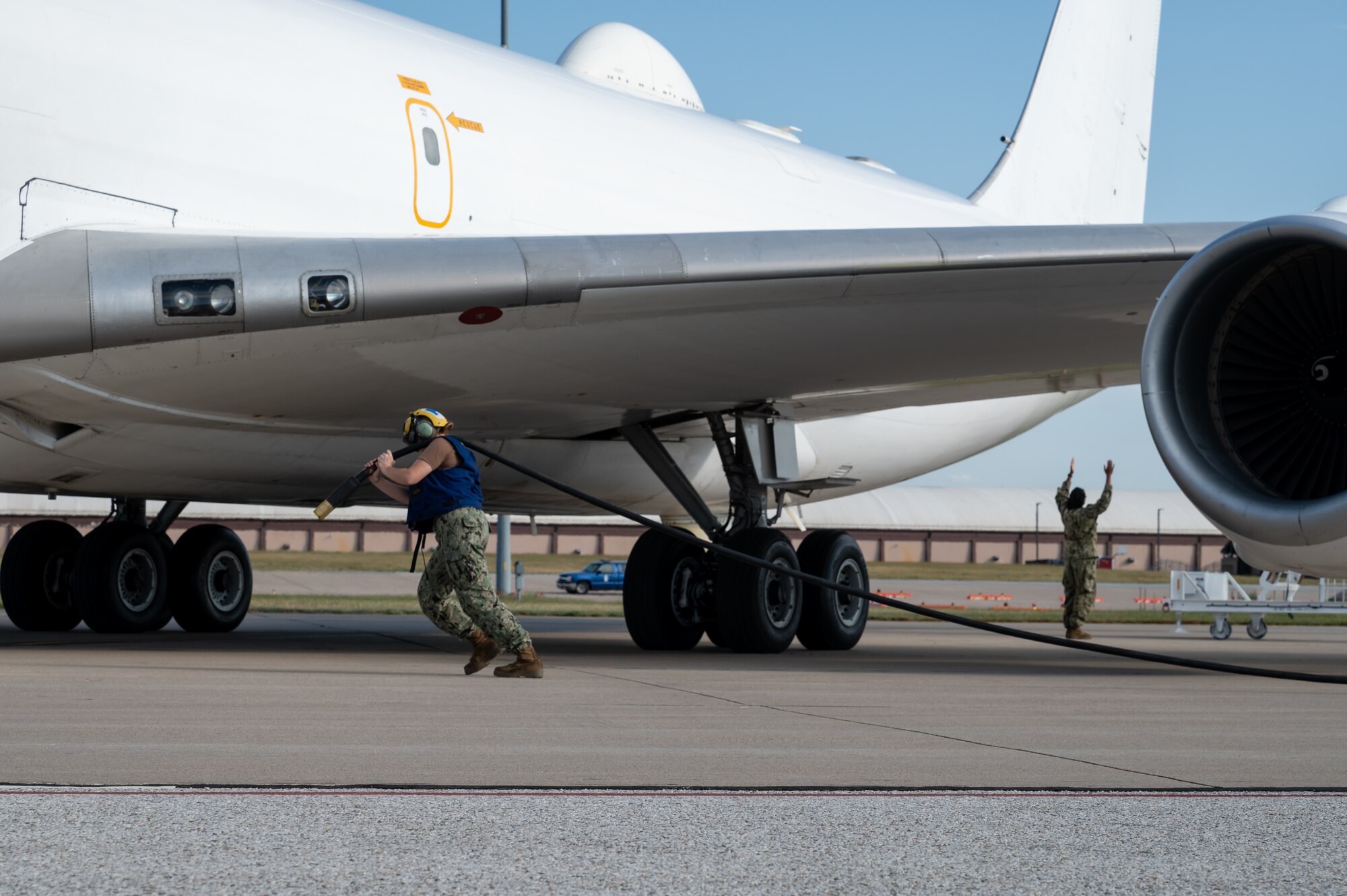 An aviation electrician hauls a cable from a generator to a E-6B Mercury