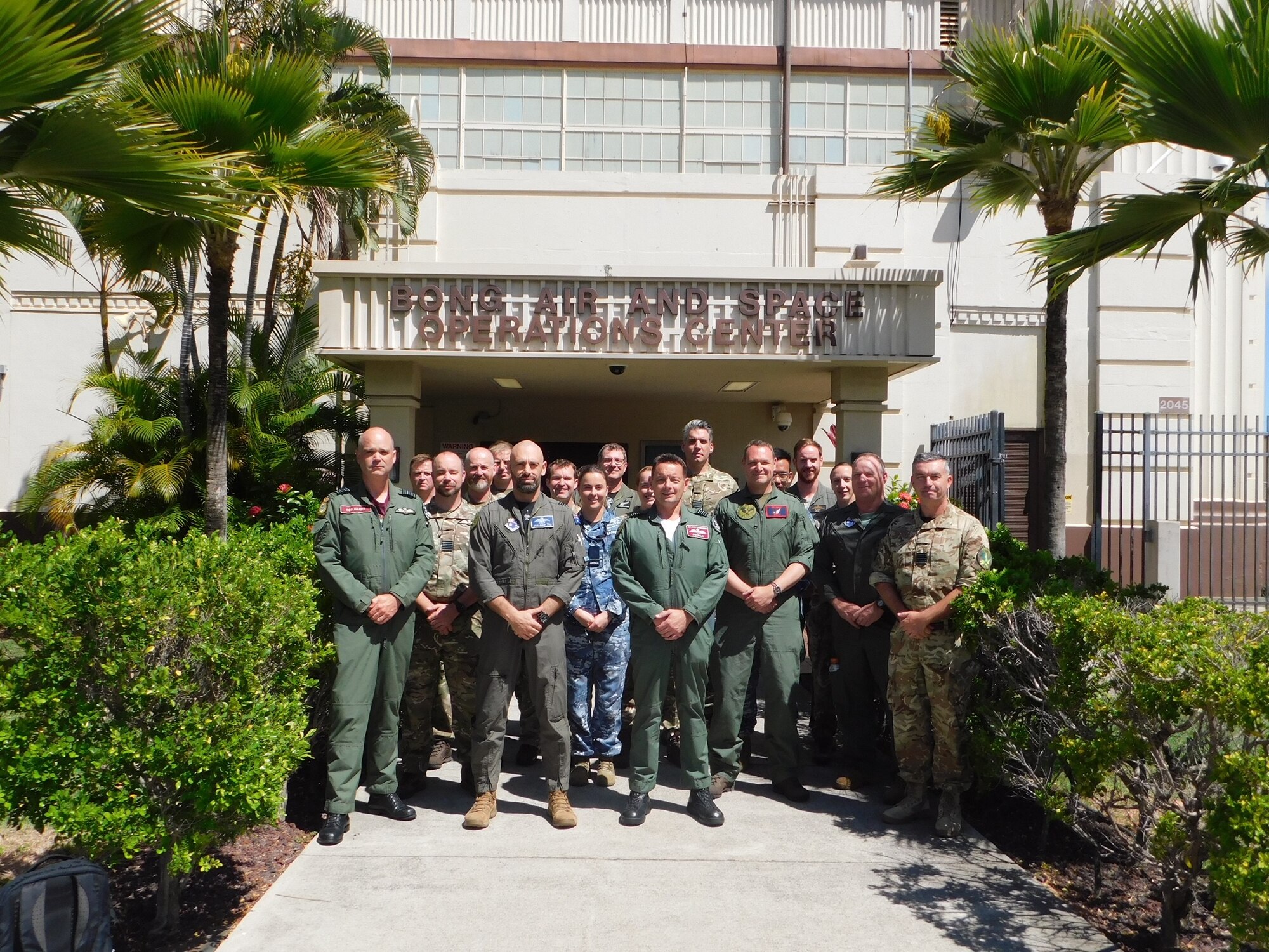 a group of uniformed Australian and United Kingdom members stand outside of a building