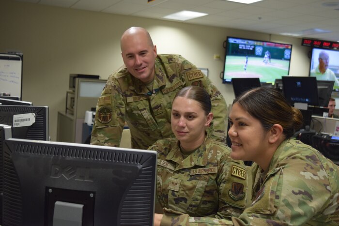 three uniformed U.S. Airmen working at computer