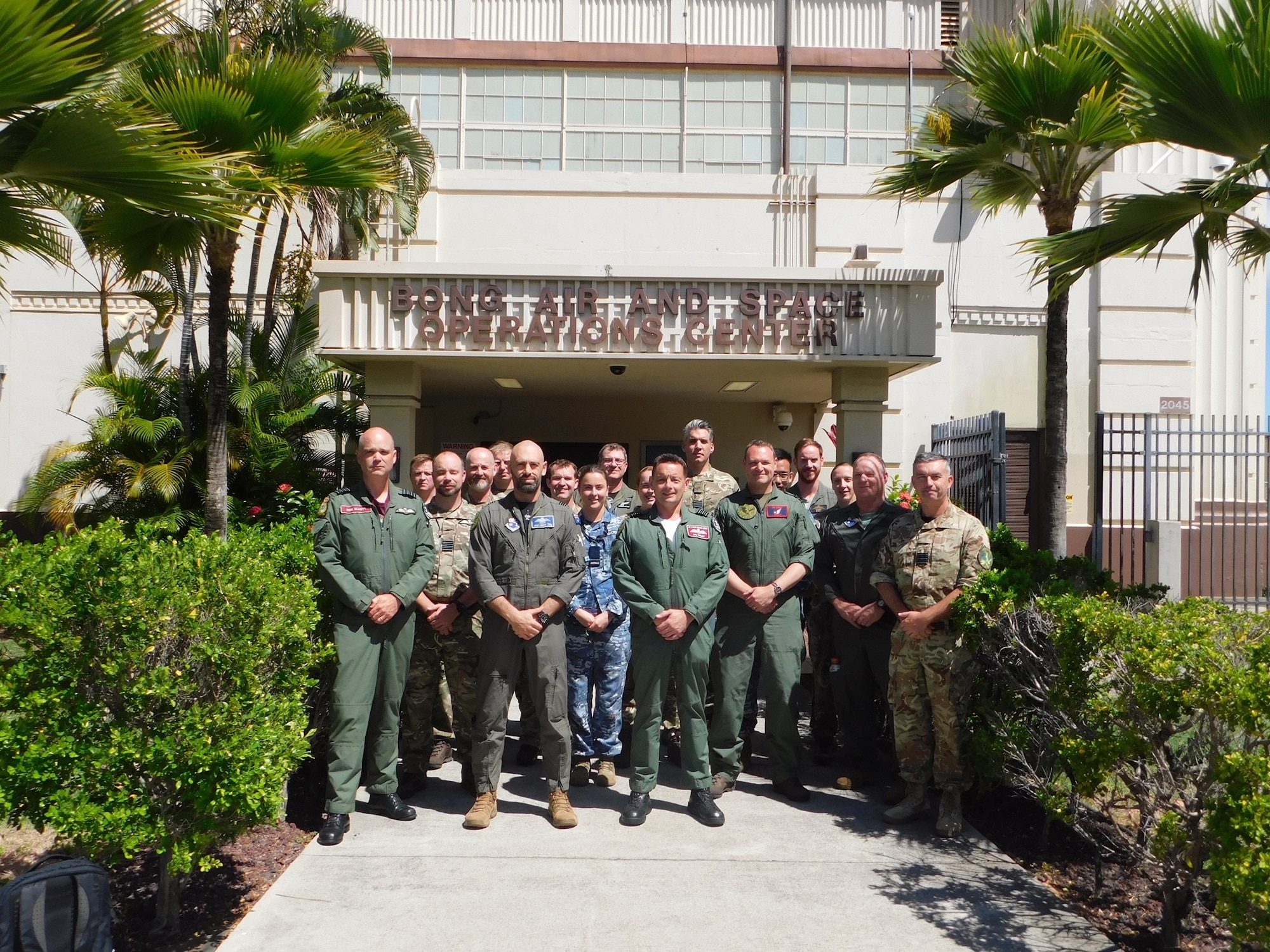 a group of uniformed Australian and United Kingdom members stand outside of a building