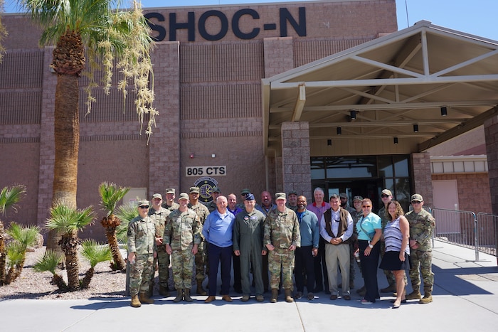 uniformed U.S. Air Force Airmen and civilians stand in front of a brick building with the signage that read SHOC-N and 805 CTS.