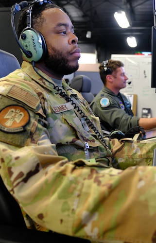 uniformed U.S. Airmen fly in simulator