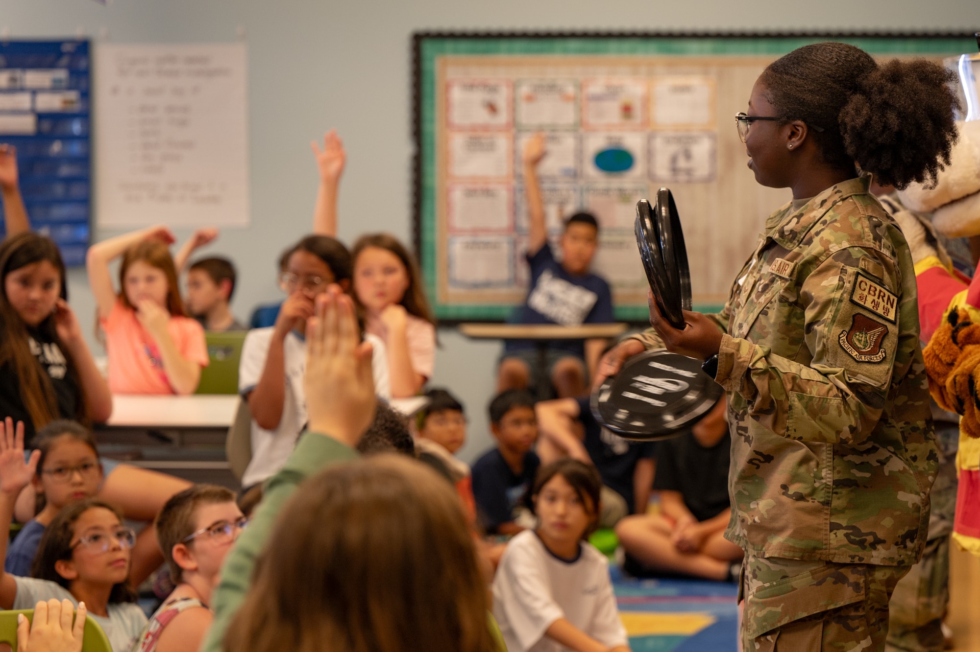 U.S. Air Force Airman 1st Class Lailia Robinson, 51st Civil Engineer Squadron emergency management apprentice, tosses frisbees to Osan Elementary School students at Osan Air Base, Republic of Korea, Sept. 18, 2024. Airmen assigned to the 51st CES visited OES to educate students on natural disaster preparedness and offer safety advice. These outreach events highlight the 51st Fighter Wing's dedication to community safety, equipping students with vital knowledge and skills to handle natural disasters with confidence. (U.S. Air Force photo by Senior Airman Brittany Russell)