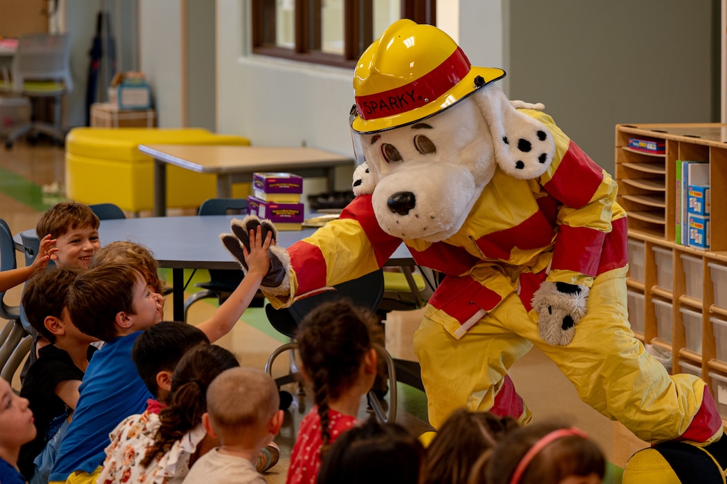 Osan Elementary School students high-five Sparky the Fire Dog at Osan Air Base, Republic of Korea, Sept. 18, 2024. U.S. Air Force members assigned to the 51st Civil Engineer Squadron visited OES to brief the students on natural disaster preparedness and safety tips. This initiative underscores the 51st Fighter Wing's commitment to fostering a culture of safety and awareness, ensuring that young minds are equipped with essential skills and knowledge for emergency preparedness. (U.S. Air Force photo by Senior Airman Brittany Russell)