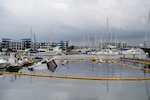A sunken vessel is seen with boom surrounding it in a marina.