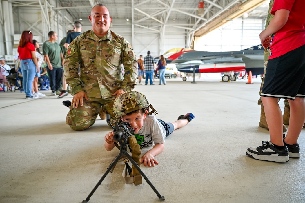 Technical Sgt. Christopher Cordova, a 433rd Security Forces Squadron fire team leader, gives the son of an Alamo Wing Reserve Citizen Airman the opportunity to interact with an M249 Squad Automatic Weapon during the wing’s Family Day at Joint Base San Antonio-Lackland, Texas Sept. 15, 2024.