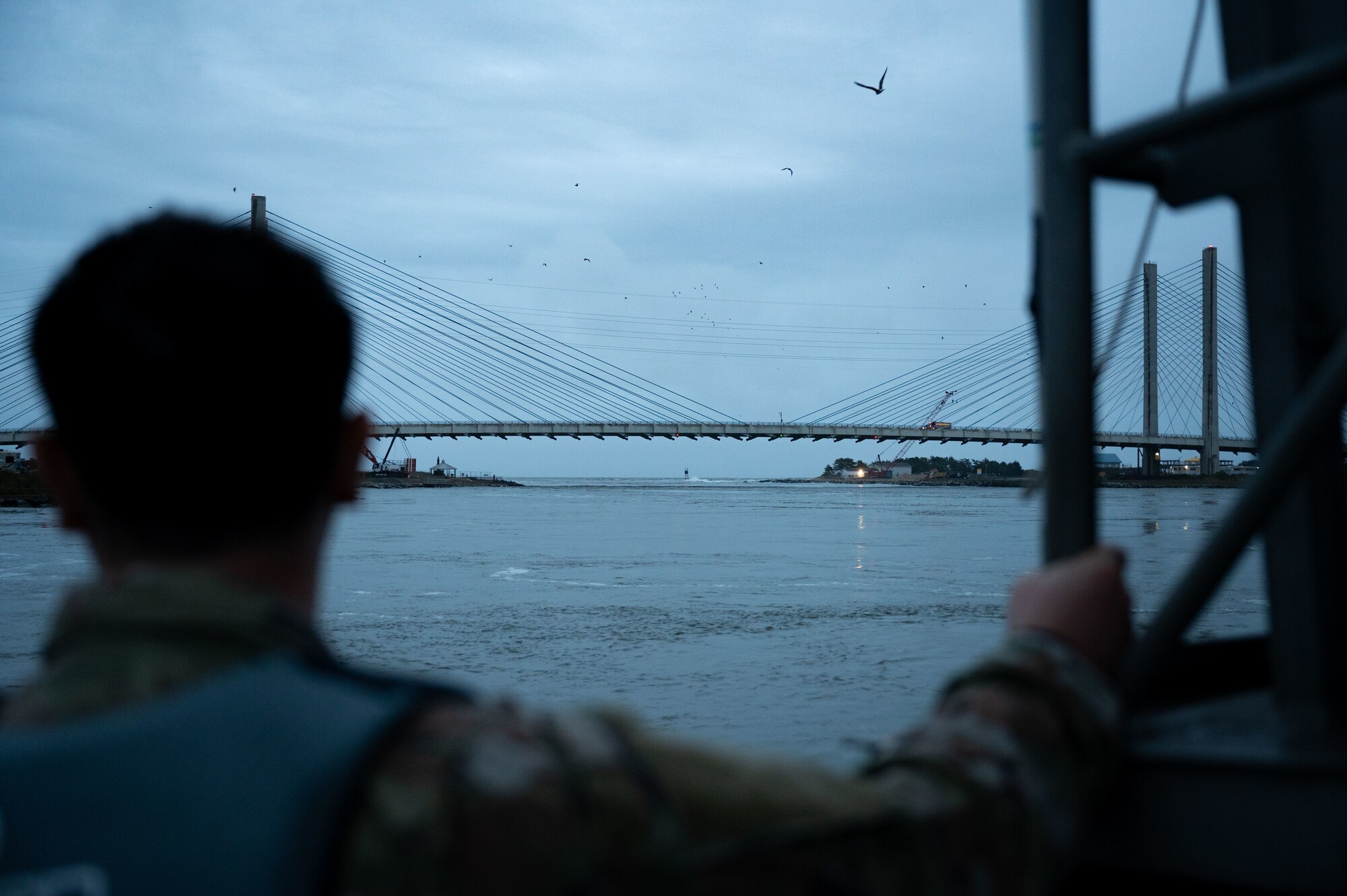 A member of Exercise Castaway 24-4 looks over the inlet from a U.S. Coast Guard boat after pulling away from U.S. Coast Guard Station Indian River Inlet, Rehoboth Beach, Delaware, Sept. 18, 2024. Castaway 24-4 was a total force interagency training exercise designed to test and execute search and rescue procedures. (U.S. Air Force photo by Airman Liberty Matthews)