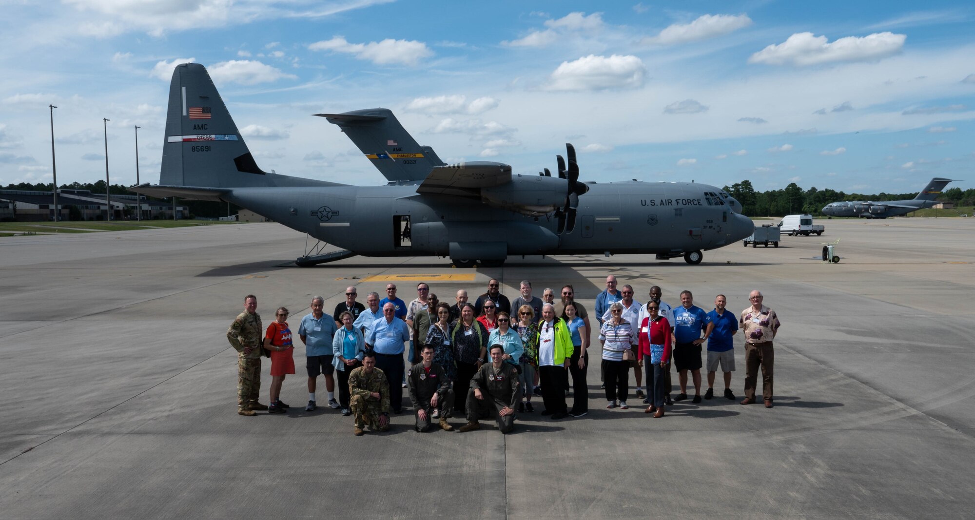 A group of veterans pose for a group shoot infront of a plane.