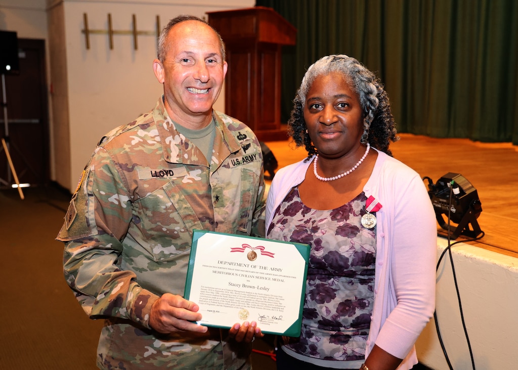 A woman receives a certificate from a man in an Army uniform