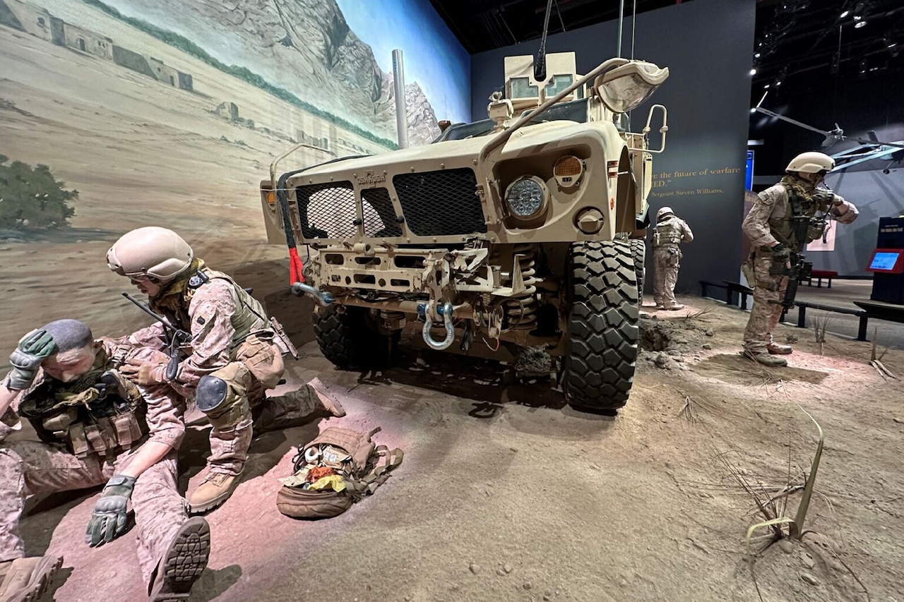 Mannequins in Marine Corps uniforms work around a military vehicle in a museum exhibit.
