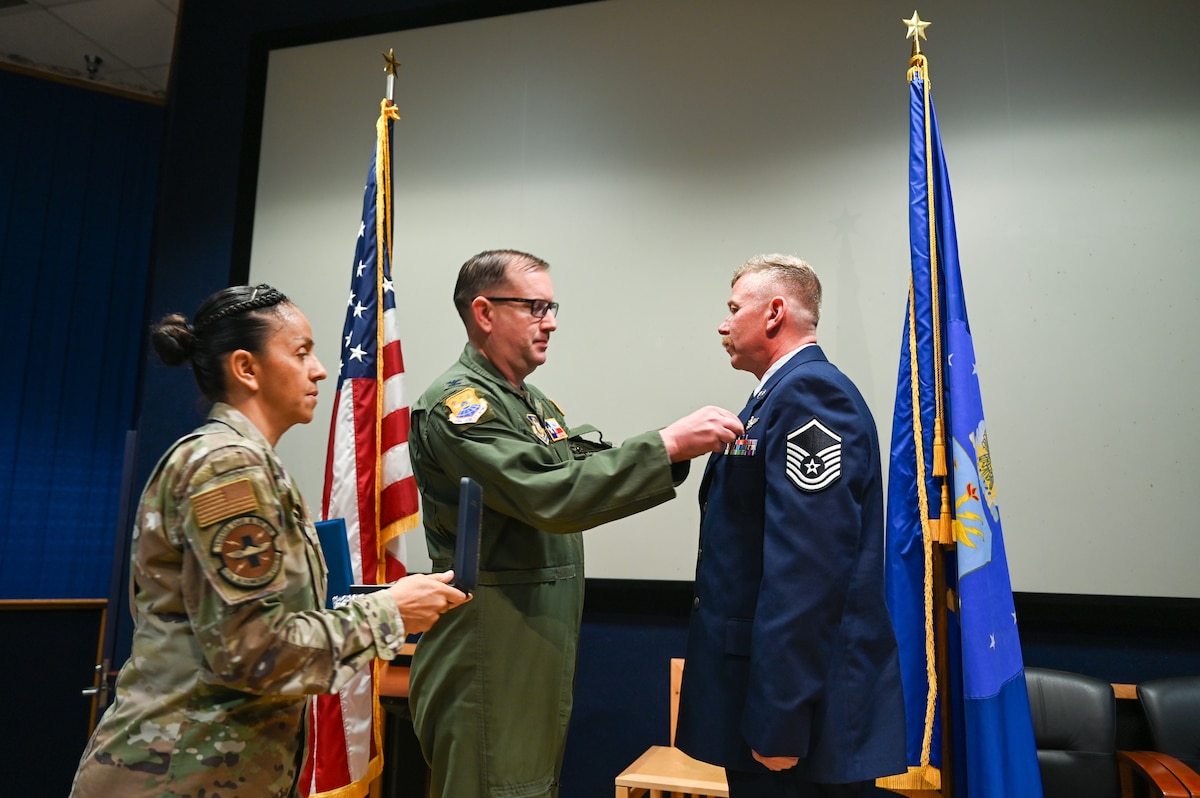 Master Sgt. Jeanett Vielman, 433rd Aeromedical Evacuation Squadron first sergeant, and Col. Douglas Jeffrey, 433rd Airlift Wing commander, present the Distinguished Flying Cross to Master Sgt. Raymond Johnson, a 433rd AES aeromedical evacuation technician, during a ceremony at Joint Base San Antonio-Lackland, Texas Sep. 12, 2024.