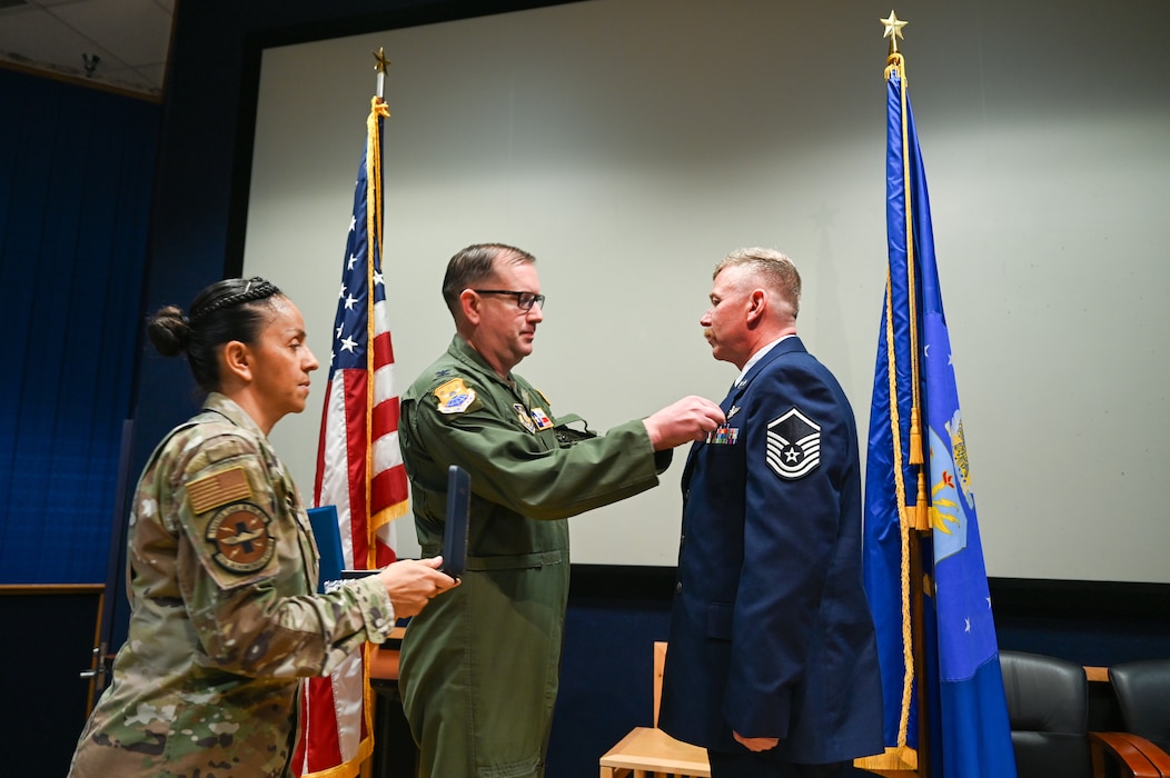 Master Sgt. Jeanett Vielman, 433rd Aeromedical Evacuation Squadron first sergeant, and Col. Douglas Jeffrey, 433rd Airlift Wing commander, present the Distinguished Flying Cross to Master Sgt. Raymond Johnson, a 433rd AES aeromedical evacuation technician, during a ceremony at Joint Base San Antonio-Lackland, Texas Sep. 12, 2024.