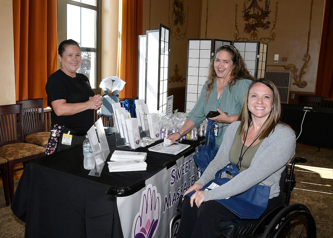 One woman standing and one woman in a wheelchair in front of an information table.
