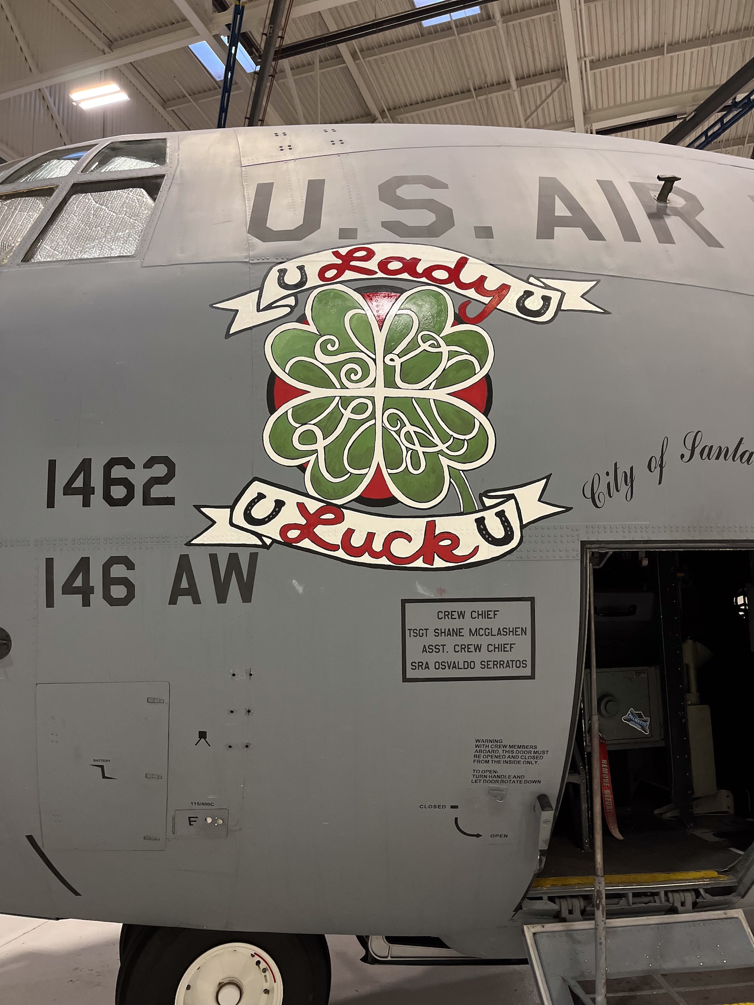 Nose art with a four-leaf clover and the words lady luck are painted on the side of a C-130J aircraft.