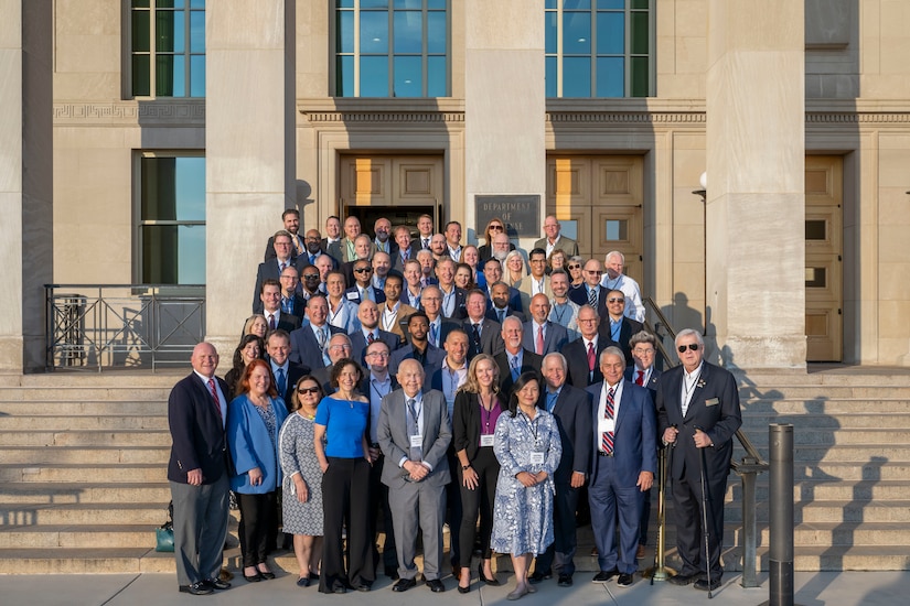 A large group poses for a photo on the Pentagon steps.