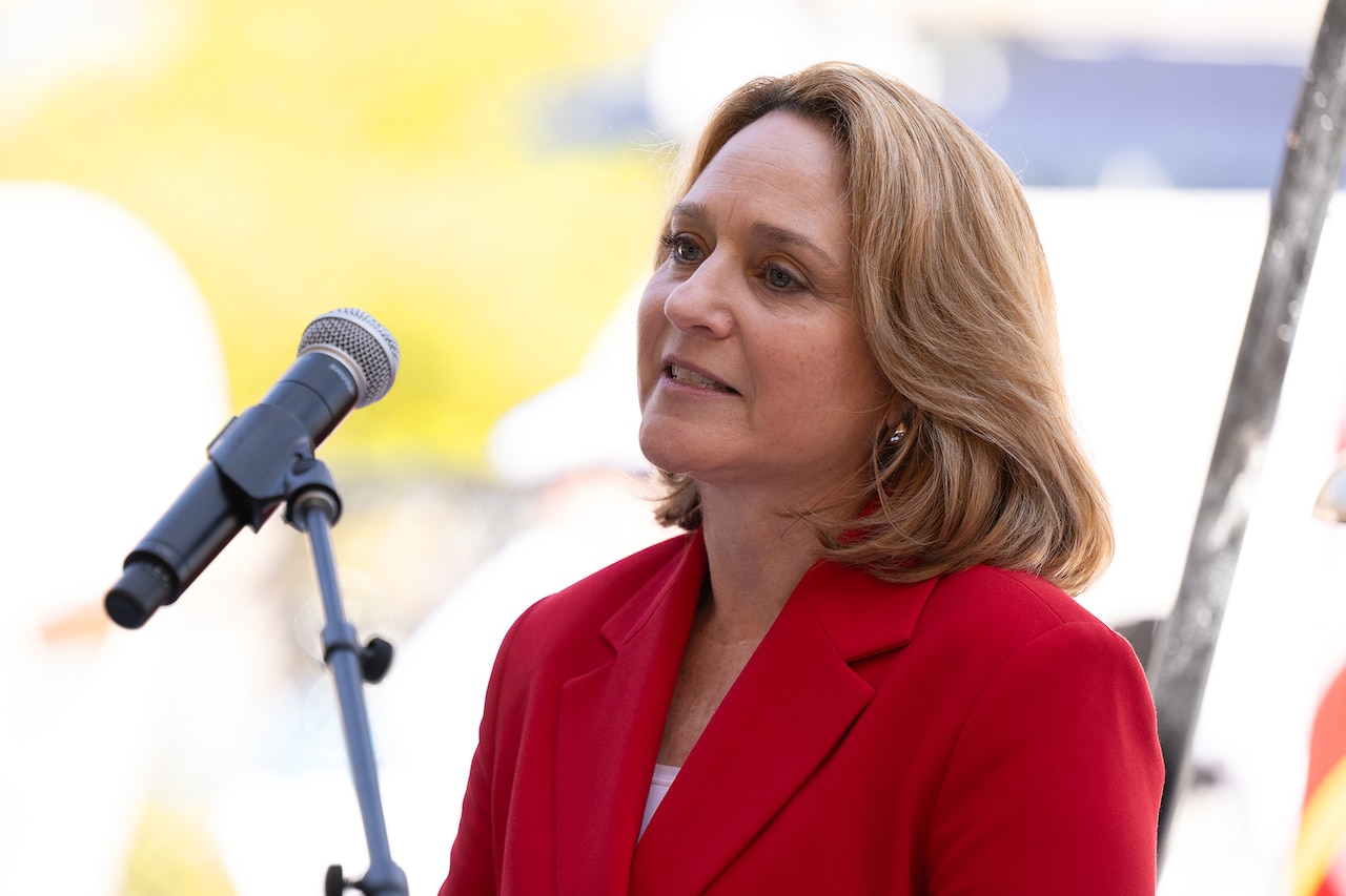 A medium close shot of a civilian in a red suit speaking into a mic.