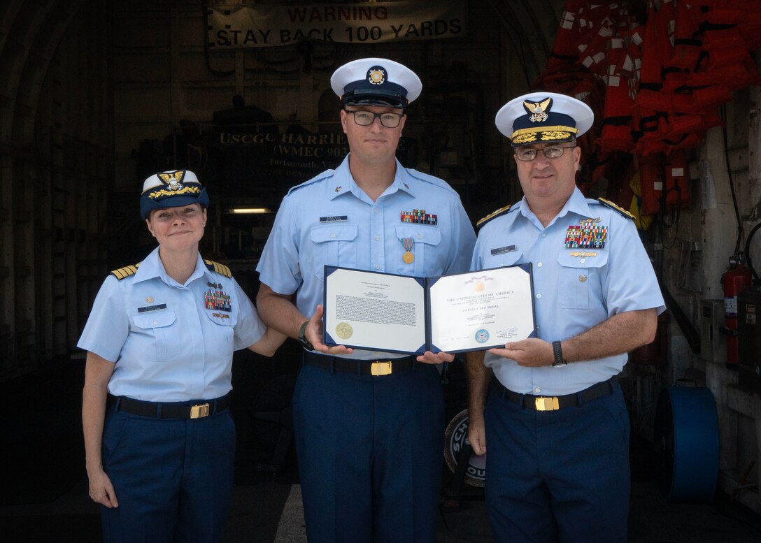 Three Coast Guard members stand with a certificate.