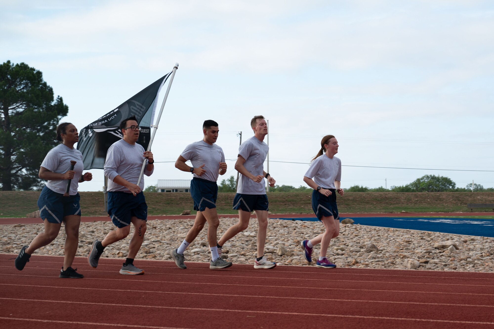 U.S. Air Force Airmen carry the POW/MIA baton and flag during the POW/MIA 24-Hour Run and Name Reading at the Mathis Fitness Center outdoor track at Goodfellow Air Force Base, Texas, Sept. 20, 2024. The baton holds the names of all the service members who were Prisoners of War and still Missing in Action. (U.S. Air Force photo by Airman 1st Class Brian Lummus)
