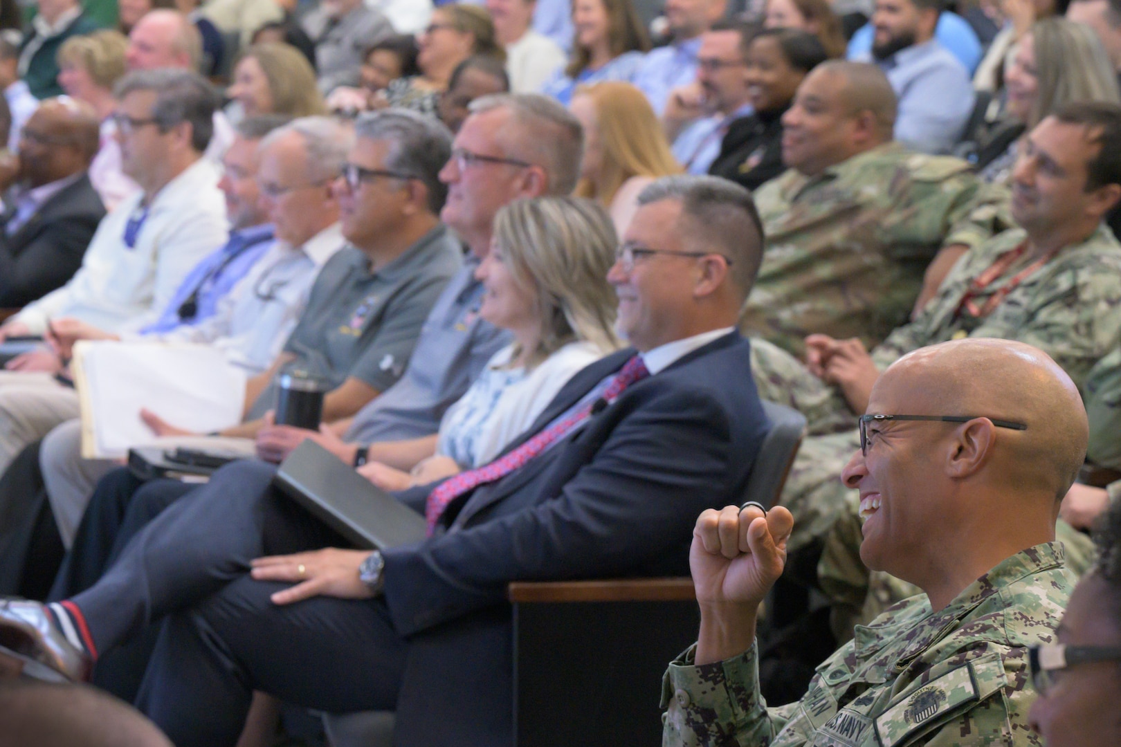 Defense Logistics Agency Energy employees laugh while watching videos of agency awardees.